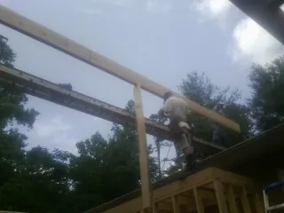 Carpenter setting a ridge beam over a new addition frame — Ice Dam Removal by Roofing Brothers in Eden